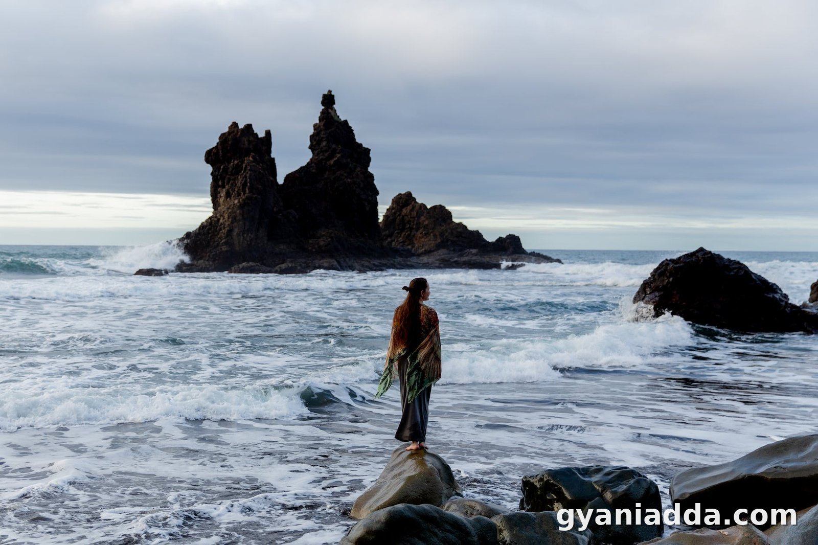 unrecognizable female tourist standing on rocky coast