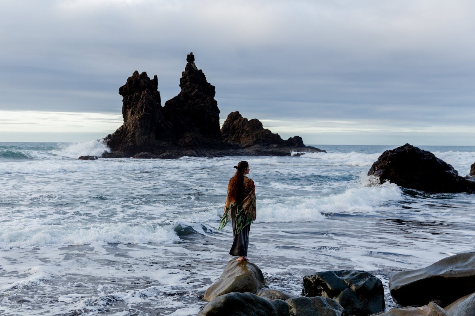 unrecognizable female tourist standing on rocky coast